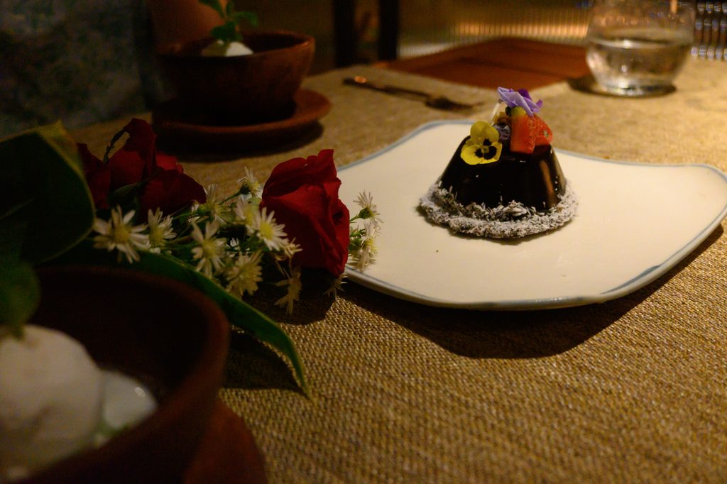 黒い三角錐のバースデーケーキ。バラの花で飾られている